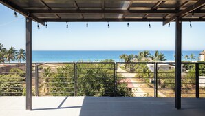 Eine Terrasse im Freien mit Blick auf den Ozean und Palmen.