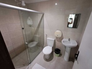 A bathroom with a glass-enclosed shower, a toilet, a sink, and a trash bin. - Pousada Recanto do Aconchego (Ipojuca)