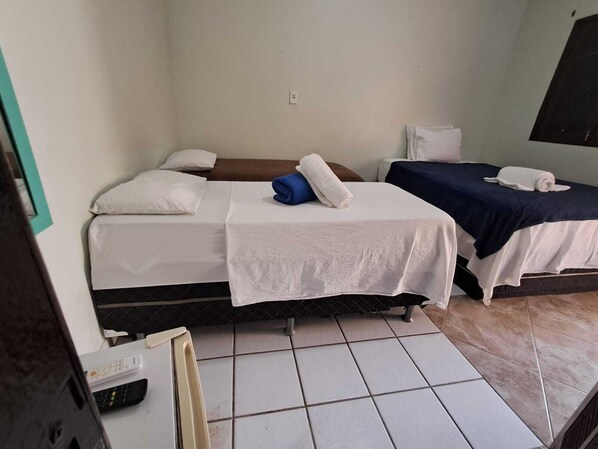 A room with two beds, each with white bedding and pillows, a small table, and a tiled floor. - Pousada Recanto do Aconchego (Ipojuca)