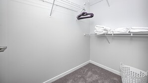 A laundry room with white walls, a grey carpet, and a white laundry basket. - Comfy Cozy - 2King bed/2bth Fishers (Fishers)