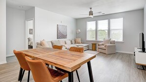 A modern living room with a wooden dining table, two sofas, and a ceiling fan. - Comfy Cozy - 2King bed/2bth Fishers (Fishers)