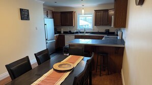 A modern kitchen with dark wooden cabinets, a central island, and a dining area with a table set for four.