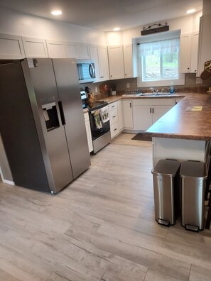 A modern kitchen with white cabinets, stainless steel appliances, and a large window. - Newly renovated 5 bedroom pet friendly house in Keuka NY. First floor ensuite (Keuka Park)