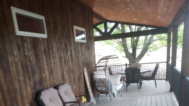 Eine Holzdar Terrasse mit zwei Stühlen, einem Tisch, einem Willkommensschild und einem Baum im Hintergrund.