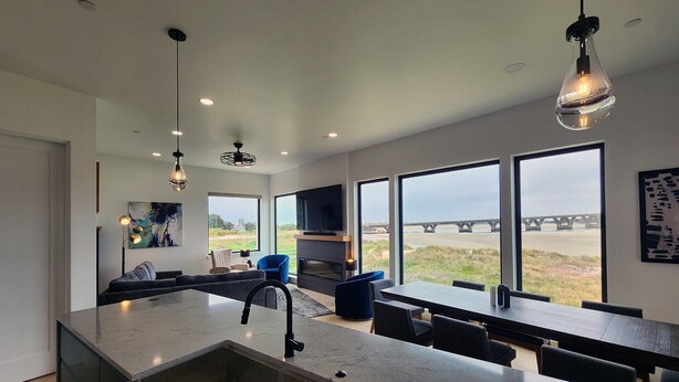 A modern kitchen with a large island, built-in appliances, and a large window overlooking a bridge. - Spectacular Bridge and Bay Views! Bayfront, Hot Tub, Dog Friendly, Fireplace! (Waldport)