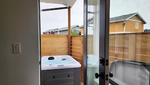A hot tub with a control panel, a wooden fence, and a view of houses in the background. - Hot Tub! Dog Friendly! Short Walk to Sandy Beach! (Waldport)