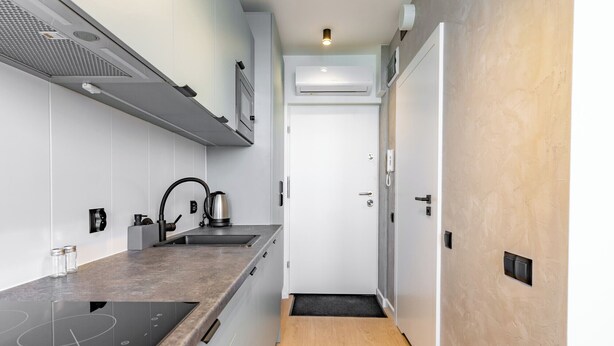 A modern kitchen with a built-in stove, a kettle, and a sink.