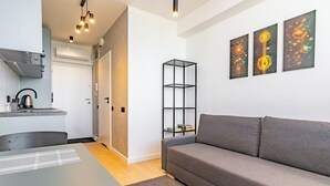 A modern living room with a grey sofa, a coffee table, and a bookshelf.