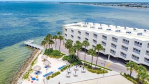 Un hotel frente a la playa con piscina, palmeras y vistas al océano.