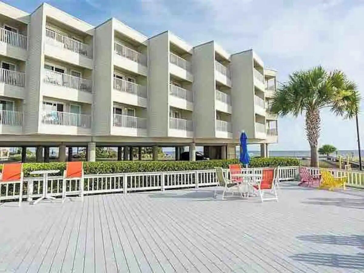 A multi-story hotel with balconies, outdoor seating, and a view of the ocean.