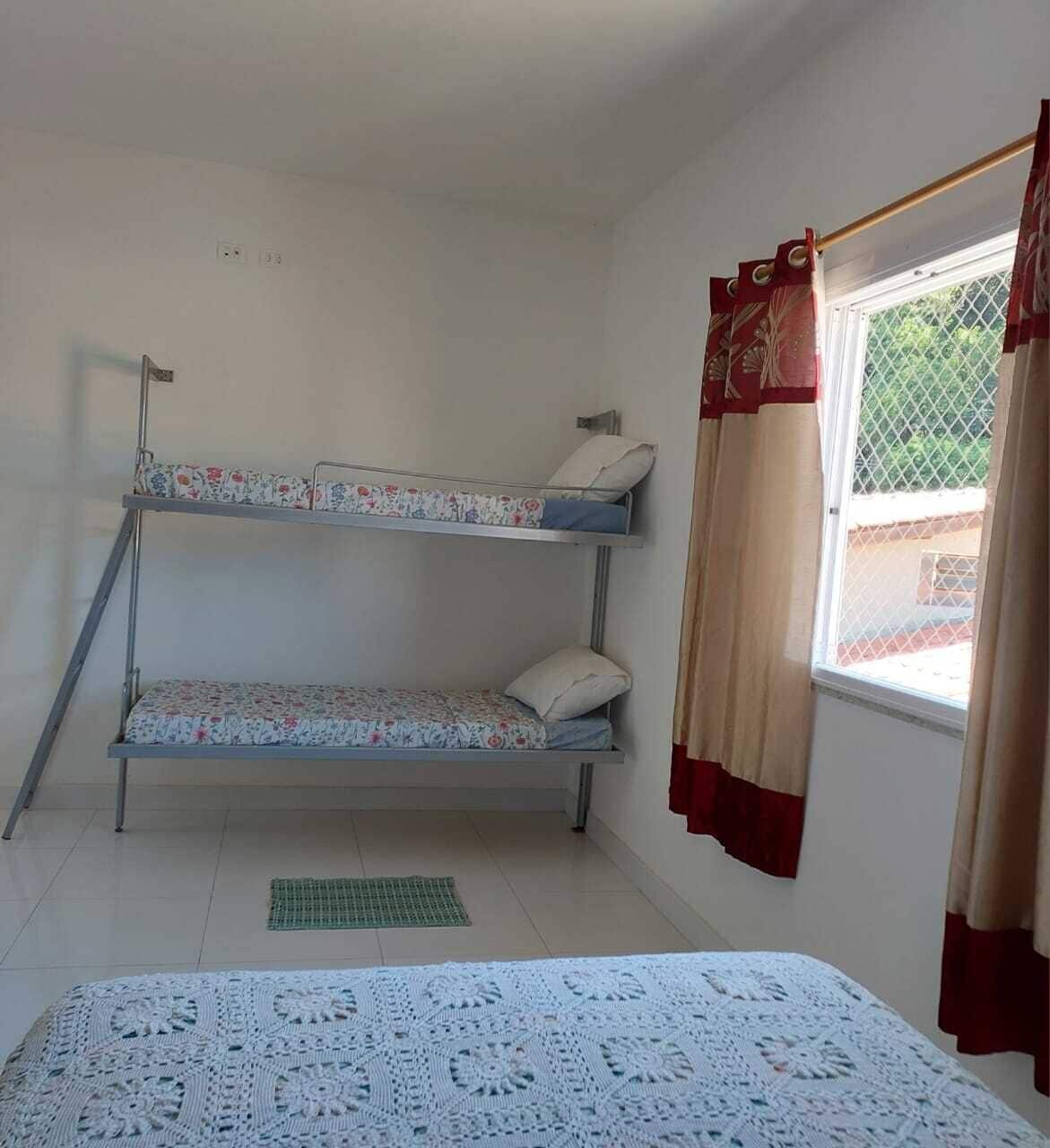 A bunk bed with floral bedding, a window with curtains, and a patterned bedspread.