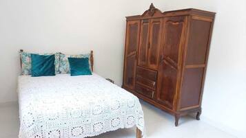 Quarto com uma cama, guarda-roupa de madeira e um tapete estampado.