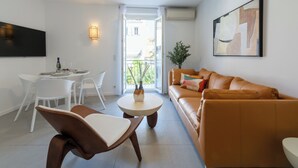 A modern living room with a sofa, chairs, a dining table, and a TV.
