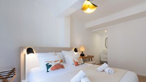 A neatly arranged hotel room with a large bed, bedside lamps, a wooden chair, and a small table with a lamp.