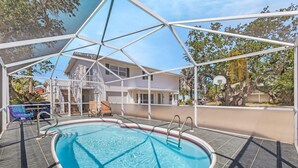 An outdoor swimming pool with a covered area, a basketball hoop, and a staircase leading to a house.