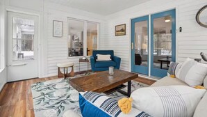 A cozy living room with a blue armchair, a wooden coffee table, and a patterned rug. - Cozy Freeport Bungalow (Freeport)
