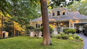 A house with a front porch, a garage, and a well-maintained lawn. - Cozy Freeport Bungalow (Freeport)