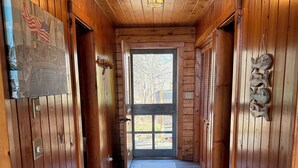 A wooden hallway with a rug, a door with a view to the outside, and a wall-mounted American flag.