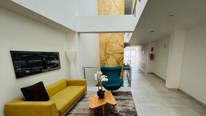 Un intérieur moderne avec un canapé jaune, un fauteuil bleu, une table basse en bois et une grande carte accrochée au mur.