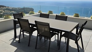 Une terrasse avec une table et des chaises, offrant une vue sur un paysage côtier.