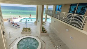 Un espace piscine d’hôtel comprenant un jacuzzi, des chaises longues et une vue sur l’océan.