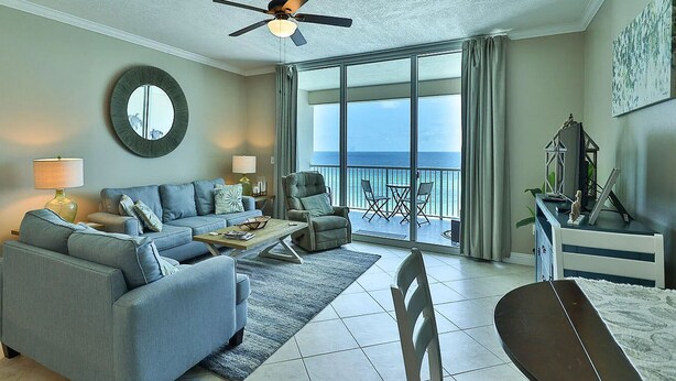 Un salon comprenant un canapé, des fauteuils, une table basse et un balcon avec vue sur l’océan.