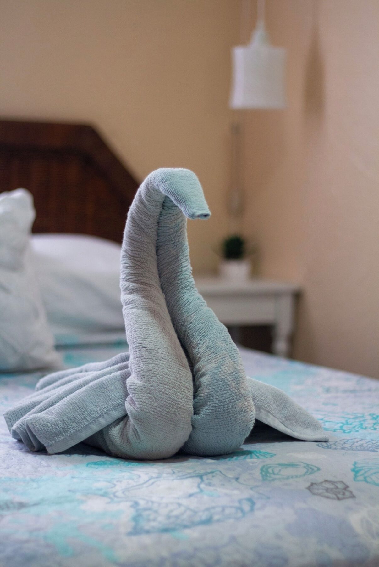Una cama con una colcha estampada y una toalla doblada en forma de cisne.