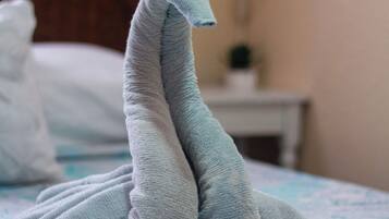 Una cama con una colcha estampada y una toalla doblada en forma de cisne.