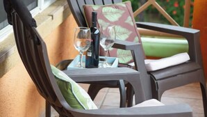 A balcony with two chairs and a table, each with a cushion. A bottle and glasses are on the table. - Island Comfort 800 Ft. from West Bay Beach — 2BR Gem with Generator (Roatan)