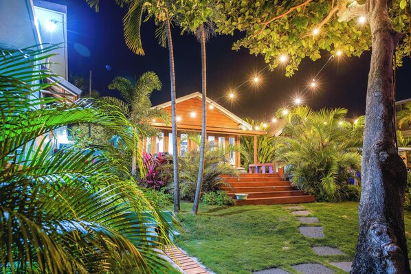 A well-lit building with a wooden exterior, surrounded by lush greenery and a stone pathway leading to the entrance. - 1 bedroom Luxury White Sand Beach Villa with Chef (Ocho Rios)