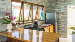 Eine Küche mit Holztischplatte, einem Herd, einem Kühlschrank und einem Fenster mit Holzrahmen.