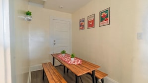 Un comedor con una mesa de madera y bancos, una puerta blanca y dos lámparas fijadas a la pared.