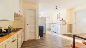 Cocina compacta con armarios blancos, pileta de acero inoxidable y encimera de madera.