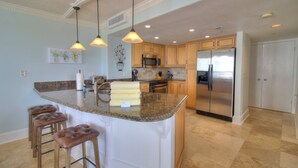 A kitchen with a central island, stainless steel appliances, and pendant lighting.