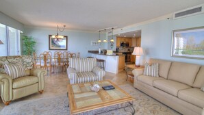 A living room with a sofa, armchairs, a coffee table, and a dining area with chairs and a table.