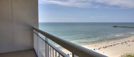 Ein Balkon mit Blick auf einen Strand, einen Steg und das Meer.