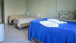 A room with two beds, one with a blue bedspread and the other with a floral bedspread. There is a white air conditioning unit on the wall, and the room has a tiled floor. - Pousada Aconchego do Porto (Ipojuca)