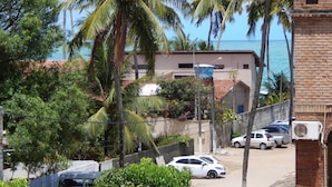 A residential area with a view of the ocean, palm trees, and parked cars. - Pousada Aconchego do Porto (Ipojuca)