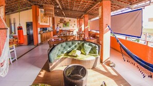 A spacious indoor area with a high ceiling, wicker furniture, and a hammock. - Pousada Aconchego do Porto (Ipojuca)