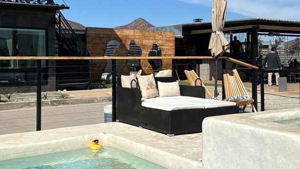 Zona de piscina con sillas de descanso, una pérgola y vistas a la montaña.