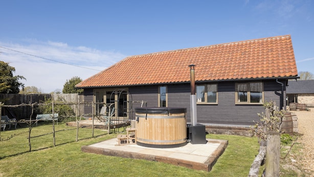 A house with a tiled roof, a wooden hot tub, and a fenced yard. - Stylish cottages, countryside views, wood burning hot tubs, 20 mins to Cambridge (Royston)