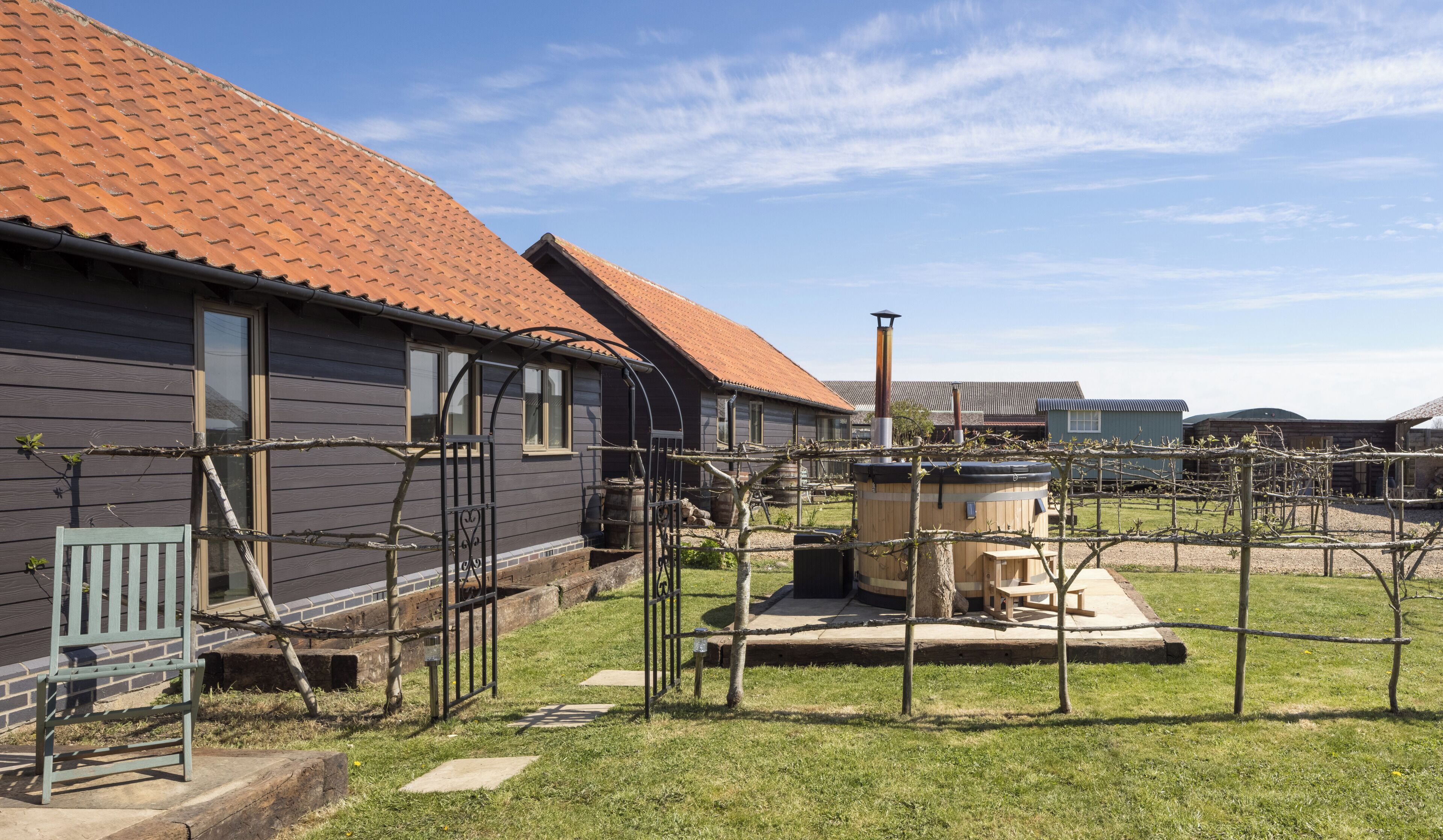 A row of houses with red-tiled roofs, a wooden bench, and a hot tub in the yard.