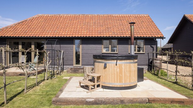 A house with a tiled roof, a wooden barrel, and a bench. - Stylish cottage, countryside views, wood burning hot tub, 20 mins to Cambridge (Royston)