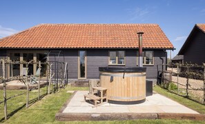 A house with a tiled roof, a wooden barrel, and a bench.