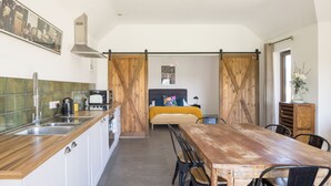 A compact kitchen with a wooden countertop and a dining area with a wooden table and chairs. - Stylish cottage, countryside views, wood burning hot tub, 20 mins to Cambridge (Royston)