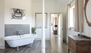 A modern bathroom with a freestanding bathtub, a large mirror, and a wooden cabinet.