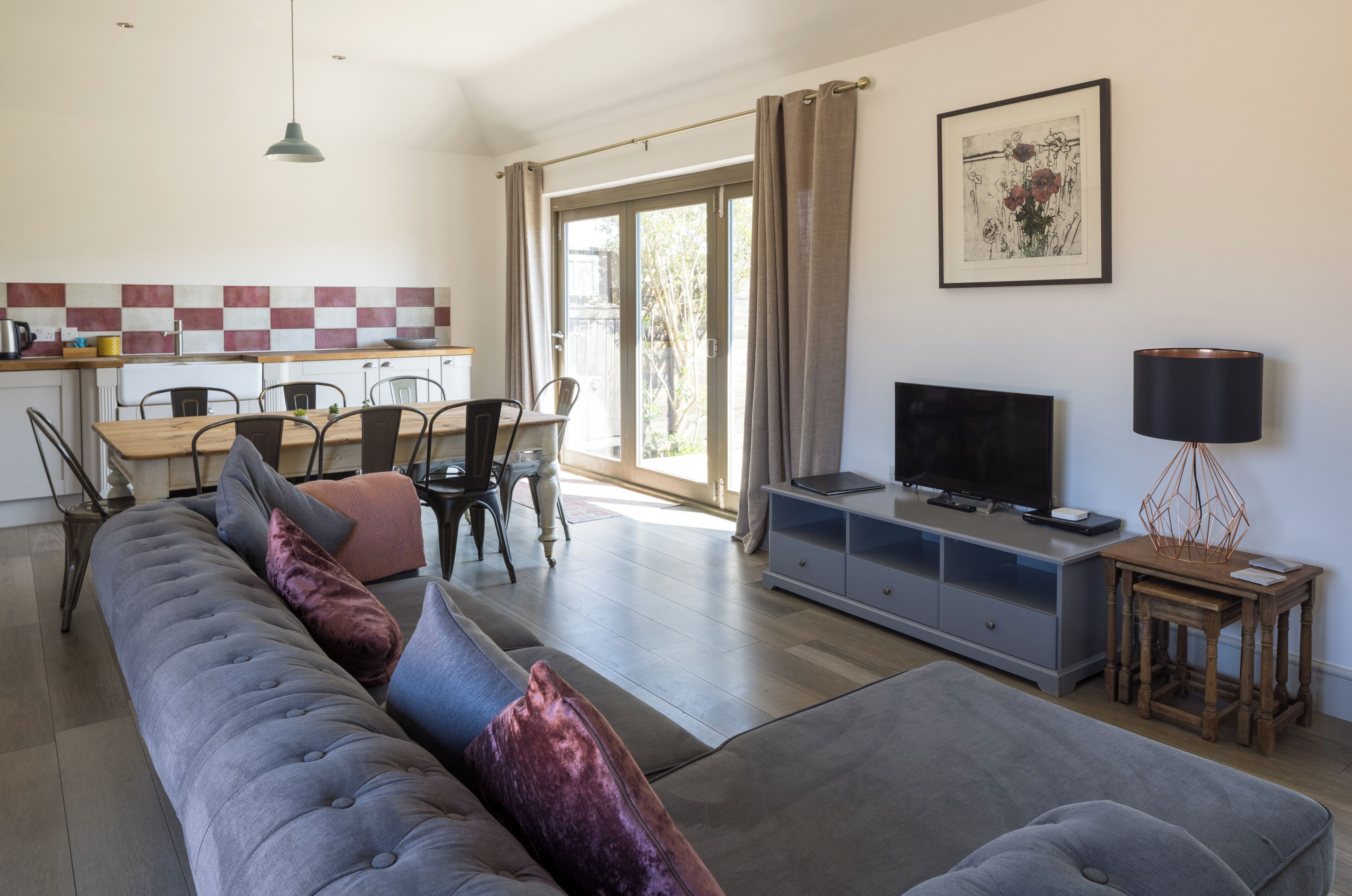 A modern living room with a grey sectional sofa, a TV, and a wooden side table.