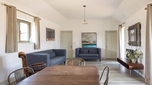 Un salon spacieux avec une table à manger en bois, deux canapés et un grand tableau accroché au mur.