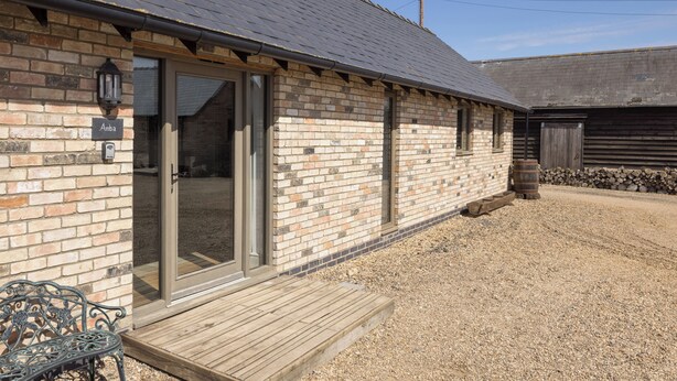 Un bâtiment en briques doté d’une terrasse en bois et d’une porte-fenêtre coulissante.