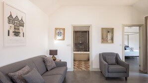 A modern living room with a grey sofa, a grey armchair, a TV, and a painting on the wall. - Stylish cottage, courtyard views, countryside location, 20 mins to Cambridge (Royston)